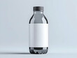 © Earny - A transparent glass bottle with a black cap, featuring a blank white label for customizable branding or product displays.