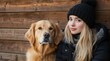 © CreativeVista - Authentic Outdoor Portrait of Young Woman Dressed in Black Knit Hat and Dark Jacket Sitting with Golden Retriever Dog by Weathered Wooden Wall