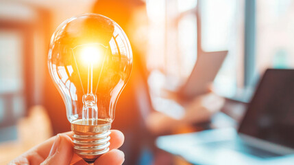 Brilliant Idea: A hand holds a glowing lightbulb, symbolizing innovation, creativity, and inspiration in the modern workplace. 