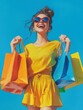 © Johannes - Happy young woman holding shopping bags against a blue background.