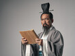 © metamorworks - 三国志に登場するような中国歴史上の偉人が竹簡の文書を読むシーン