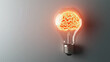 © lnsu - A lit bulb with a brain outline glowing inside, capturing the essence of imagination, creative thought, and innovation on a subtle grey backdrop.