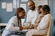© AnnaStills - Smiling healthcare worker engaging with a family in a medical setting, showing compassion and professionalism while two children and a parent observe attentively