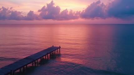 Wall Mural - A serene sunset over calm waters with a wooden pier extending into the horizon.