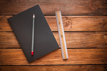 Wall Mural - Closed notebook, pencil and old ruler on a rustic wooden board