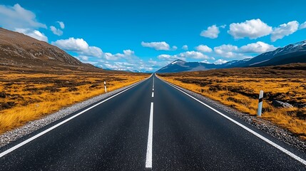 An empty road winds through a mountain pass, with a blue sky and clouds stretching above.