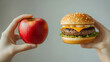 © suldev - One hand holding apple fruit, other holding hamburger. Healthy natural organic fresh vegetarian food vs unhealthy processed fast junk food meat. Nutrition diet lifestyle, fitness eating choice