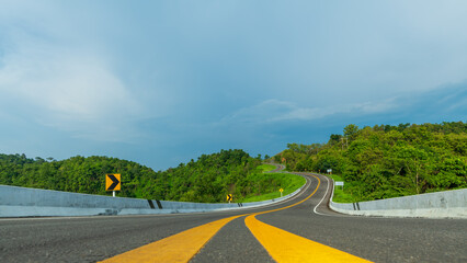 Wall Mural - long curvy forest asphalt road over the hills. beautiful curved road in the forest. side view of roa