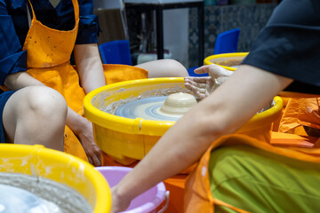 Close up of female potters hands making bowl,Two young women friends enjoying hand clay molding on pottery wheel workshop