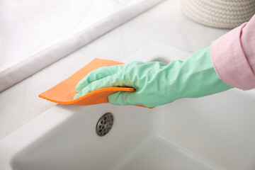 Wall Mural - Woman wiping sink with napkin in kitchen, closeup