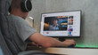© Framestock - Caucasian teenager in headphones watches educational blog about filmmaking on personal computer at home. Video hosting website with blogger content about movie or video editing displayed on PC screen.
