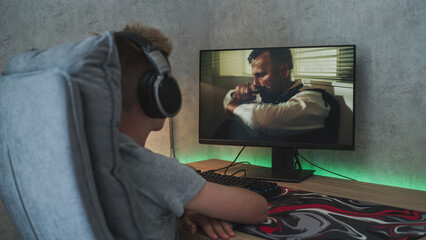 Poster - caucasian teenager in headphones watches online thriller or action film on personal computer while s