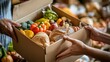 © irissca - Hands passing a Thanksgiving meal box filled with fresh produce and canned goods at a community food drive in natural light