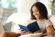 © Antonioguillem - Happy black reader reading a book at home