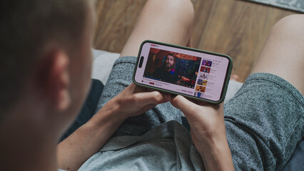 Poster - caucasian boy watches educational video of blogger about stock trading using mobile phone while sitt