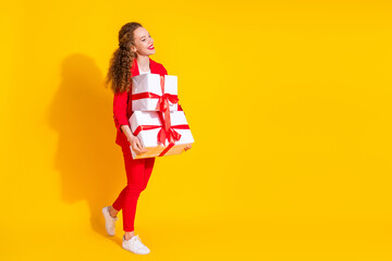 Poster - Full size photo of pretty young woman giftbox walk empty space wear red suit isolated on yellow color background