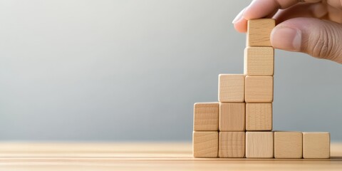 Aufkleber - Business strategy and action planning are illustrated by a hand stacking wooden blocks, symbolizing goal-setting, development, and planning for business growth.