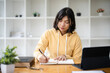 © Fahng - Woman takes notes at her home office, using tablet laptop remote work. Online education concept