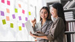 © Pichsakul - Two businesswoman reading business data on laptop and writing strategy ideas in sticky notes