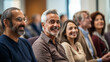 © NOPPHINAN - Group of diverse adults sitting and smiling during a seminar or conference, with a positive and engaged atmosphere.