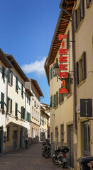 A quiet street in Tuscany, Italy, with a pizzeria sign and traditional architecture. This image is suitable for travel, culture, or city exploration content.