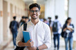 © Anand Kumar - Young Indian male student with notebooks in bright university hallway