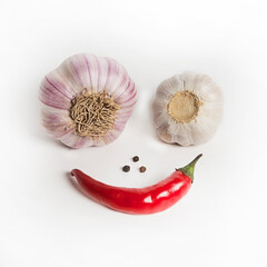 Two heads of garlic and black pepper are laid out on a white background in the form of a funny face. Harvesting in autumn. Vitamins