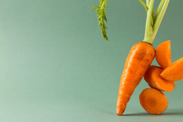 Sticker - Whole and cut fresh carrots on green background, space for text