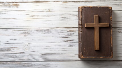 Christian cross lying on the bible on light wooden boards with space for text or inscriptions, top view
