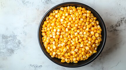 Wall Mural - A top-down view of a bowl filled with yellow corn kernels against a white marble table showcases the simplicity and beauty of food photography, perfect for culinary presentations.