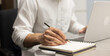 © chinnarach - close up businessman hand writing content or somethings on notebook with using laptop at wooden table at home office for people and lifestyle concept