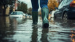 © GrayFrog - Person in green rubber boots walks thru the flooded street