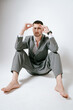 © Elina Leonova - Handsome man in grey suit sits on the floor barefoot