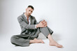 © Elina Leonova - Handsome man in grey suit sits on the floor barefoot