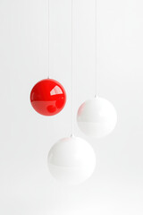 Poster - three modern hanging spherical lights, two white and one vibrant red, against a minimalistic white b