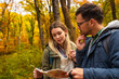 © Zoran Zeremski - Smiling couple with backpacks hiking together in forest using map for direction.
