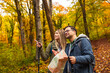 © Zoran Zeremski - Smiling couple with backpacks hiking together in forest using map for direction.