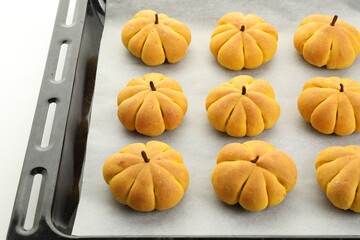 Sticker - Baking tray with tasty pumpkin shaped buns on white background, closeup