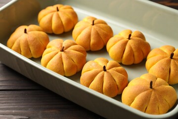 Wall Mural - Baking tray with tasty pumpkin shaped buns on wooden table, closeup