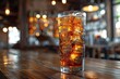 © aicandy - A glass of refreshing cola with ice sits on a wooden table in a dimly-lit, cozy bar with a warm ambiance and scattered lights in the background