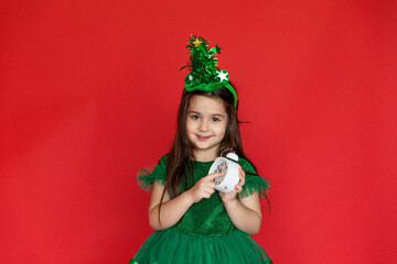 Wall Mural - Happy child little girl in Christmas tree green costume with alarm clock. Christmas eve time. Holiday concept. New year time