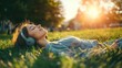 © BerkahStock - A woman relaxes on grass, listening to music with headphones as the sun sets.