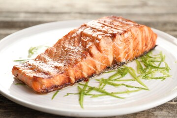 Delicious grilled salmon fillet served on wooden table, closeup