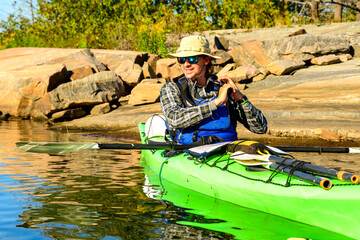 sea kayaker in green boat sits near rocky shore in georgian bay lake huron ontario room for text