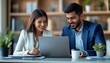 © Panuwat - Young couple sitting desk office looking laptop screen Indian financial advisors, both
