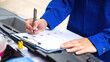 © Nattawit - Close-up at a mechanic foreman's hand is checking on multi-point car service guideline checklist form, to verify the car service quality. Expertise working action scene, selective focus.