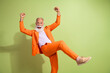 © deagreez - Portrait of aged man performer raise fists shout yes wear orange suit isolated on green color background