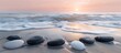 © Danish - Black and white stones arranged in a harmonious pattern on a sandy beach, washed by gentle waves under a soft pink sunrise sky, illustrating balance and serenity.