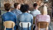 © Anna - A diverse group of individuals sits in a stylish workshop space, focused on a shared learning experience. They are dressed casually and engaged in a collaborative environment