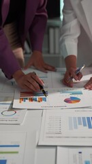 Wall Mural - Two businesswomen are collaborating on a project, carefully examining and discussing financial reports and data analysis